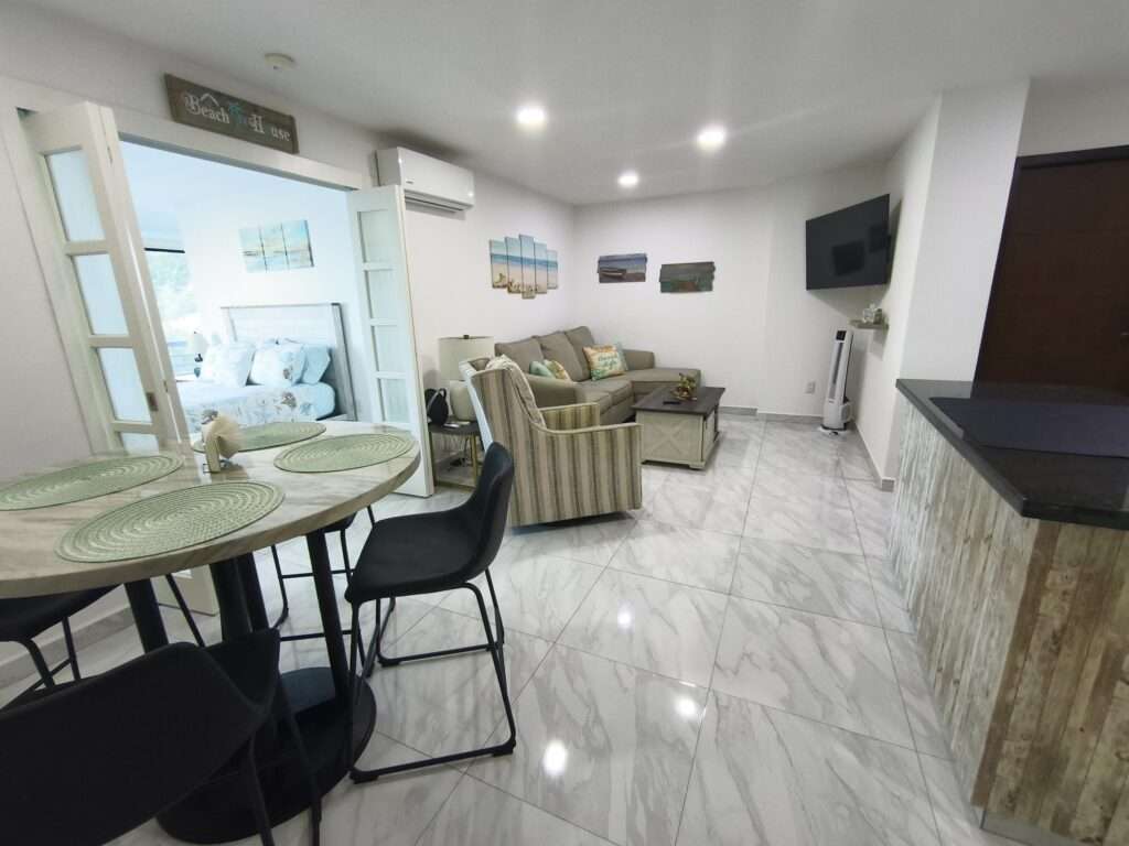 Los Cabos Morgan Residences Morgan Residences Condo 306 offers 67 m² of functional living space with one bedroom, one and a half baths, and a private balcony overlooking the city. The open floor plan connects the kitchen, dining, and living areas with marble-style tile throughout. The kitchen has granite counters, white cabinets, and an island with seating. The bedroom includes an ensuite bathroom with a walk-in shower and opens to the terrace. A separate half bath includes in-unit laundry. The building features a rooftop pool, gym, BBQ area, and – 1921 8 de Octubre, Cabo San Lucas, BS